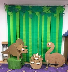 some paper cut out animals are standing in front of a green curtain and purple carpet