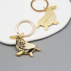 two key chains with an animal design on them, one is gold and the other is silver