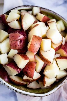 a bowl filled with sliced up potatoes on top of a tablecloth covered table cloth