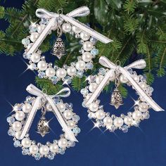 two christmas wreaths with bells and bows are hanging from a fir tree, surrounded by ornaments