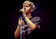 a young man holding a microphone up to his mouth while singing into the microphone on stage