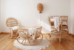 two wicker chairs and a rocking chair in a room with wood floors, white walls and wooden flooring