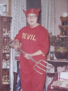 an old photo of a man in devil costume holding a hammer and wearing a pitchfork