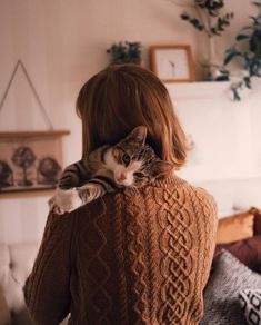 a woman holding a cat on her back