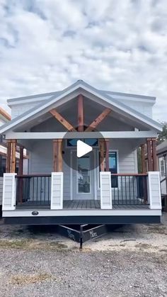 a small white house sitting on top of a gravel lot