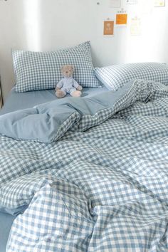 a teddy bear sitting on top of a blue and white checkered comforter set