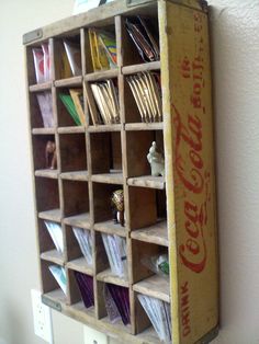 an old coca - cola crate with many cards in it is hanging on the wall