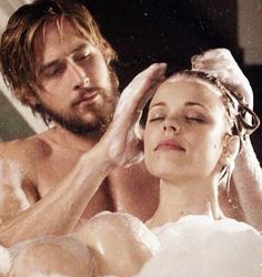 a man and woman are in the bathtub with soap on their heads, one is washing his head