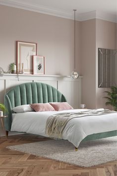 a bedroom with pink walls, white bed and green headboard in the middle of the room