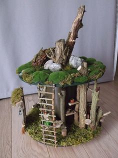 a miniature tree house with moss growing on the roof