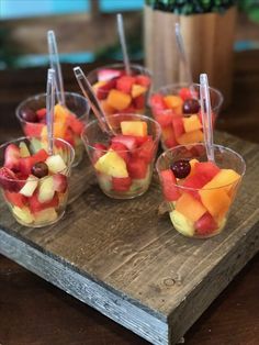 small cups filled with fruit on top of a wooden tray