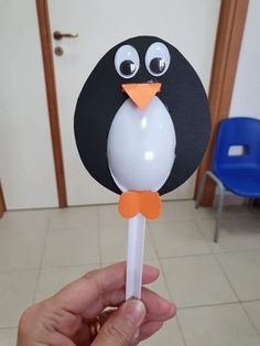 a hand holding a lollipop with a penguin on it's head and eyes