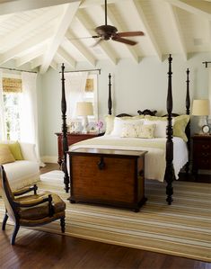 a bedroom with a bed, chair and ceiling fan in the middle of the room