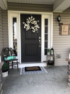 a black front door with white flowers on it and a welcome mat in the foreground