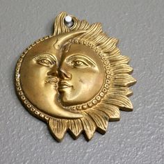 a gold sun and moon face on a white wall with a bead in the middle