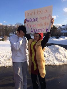 two people dressed up as hotdogs and one is holding a sign that says don't be a meme