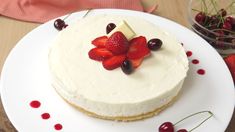 a cake with white frosting and fresh berries on top is sitting on a plate