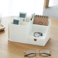 a desk organizer with cell phone, watch and other items in it on a wooden table