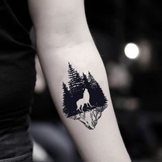 a person with a tattoo on their arm and a wolf in the woods behind them