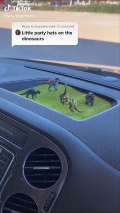 a car dashboard with an image of dinosaurs in the grass on it's screen