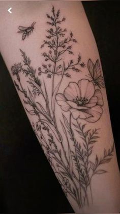 a woman's arm with flowers on it and a bee flying over the top