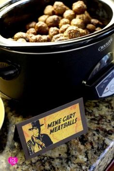 a crock pot filled with meatballs sitting on top of a counter