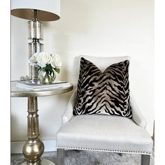 a zebra print pillow sitting on top of a white chair next to a small table