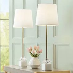 two lamps sitting on top of a table next to a vase with flowers in it