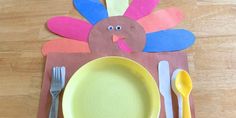 a paper turkey sitting on top of a table next to a yellow plate and silverware