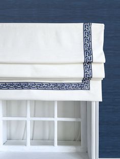 a white window with blue greek border on the valance and bottom part of it