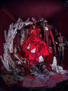 a woman in a red dress surrounded by cards and dolls