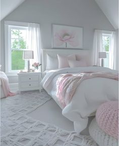 a white bedroom with pink accents on the pillows and bed linens, along with two windows