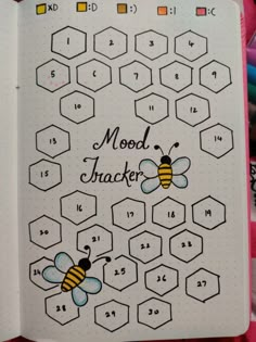 an open notebook with bees and numbers on the pages that spell out moon trackerrs