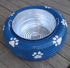 a blue and white dog bowl with paw prints on the rim is sitting on a wooden deck