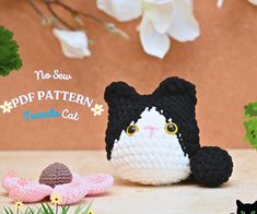 a crocheted black and white cat sitting next to flowers