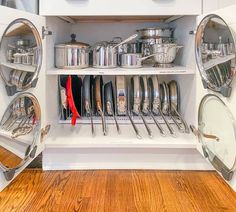 an organized kitchen with pots and pans on the shelves, in front of a wooden floor