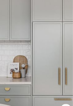 a kitchen with gray cabinets and gold handles on the doors, along with a white counter top