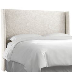 a bed with white linens and pillows on it's headboard, against a white background