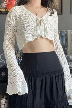 a woman wearing a white crop top and black skirt with her hands in her pockets