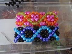 three different colored beaded bracelets sitting on top of a plastic container filled with beads