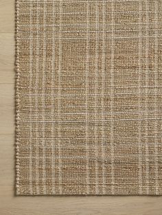 a beige and white rug on top of a wooden floor with a wood flooring board