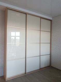 an empty room with white sliding doors and wood flooring on one side, brick wall in the background