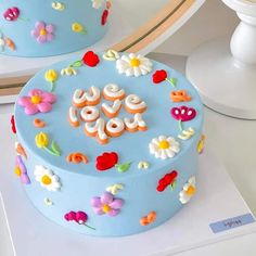 a blue cake decorated with flowers and the words love spelled on it