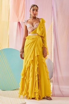 Bright yellow plain ruffled pre-draped saree crafted in georgette. Paired with a peach hand dyed blouse with cap sleeves and statement floral embroidery all over using glass beads, rain-drop pearls, tassels, a petticoat and a glass beads, rain-drop pearls leaf lines embellished waist belt. - Aza Fashions Elegant Summer Lehenga With Traditional Drape, Chiffon Saree With Ruffles In Traditional Drape, Ruffled Chiffon Saree In Traditional Drape, Wedding Chiffon Saree With Ruffles, Chiffon Ruffled Saree For Party, Fitted Chiffon Saree With Ruffles, Glamorous Pre-draped Saree With Ruffles For Festive Occasions, Glamorous Pre-draped Saree With Ruffles, Festive Gown With Ruffles And Traditional Drape