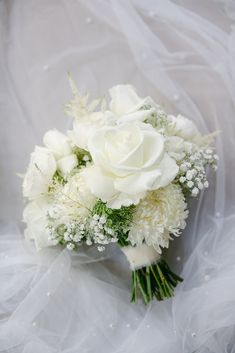 a bridal bouquet with white flowers and baby's breath on the table cloth