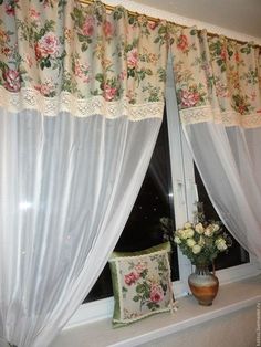 a window with white curtains and pink flowers on the windowsill next to a pillow