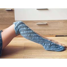 a woman's legs with crocheted socks on the floor next to a dresser