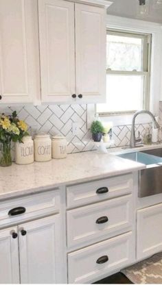 a kitchen with white cabinets, marble counter tops and stainless steel sink in the center