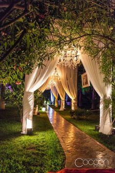 an outdoor wedding venue with white drapes and chandelier hanging from the ceiling