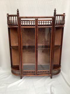 an old wooden display case with glass doors on the top and bottom shelves, in front of a white background